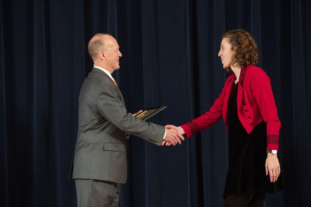 Doctor Potteiger shaking hands with an award recipeint in a black dress and red sweater